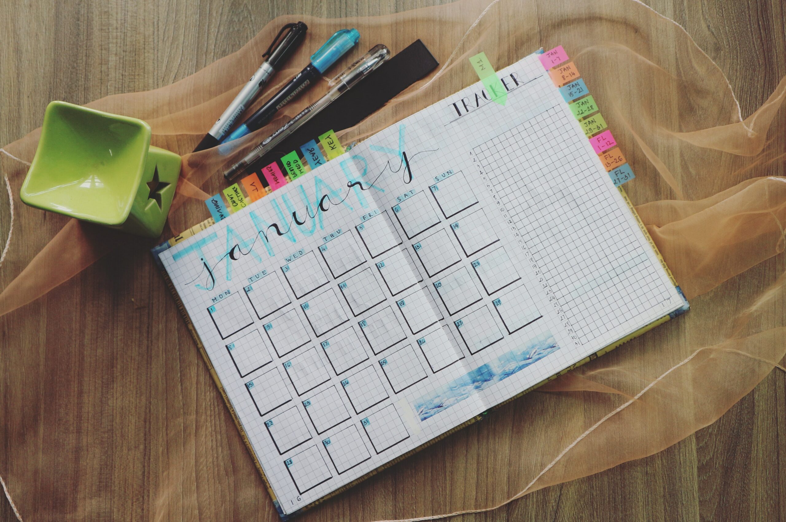 A planner on a table with pens.