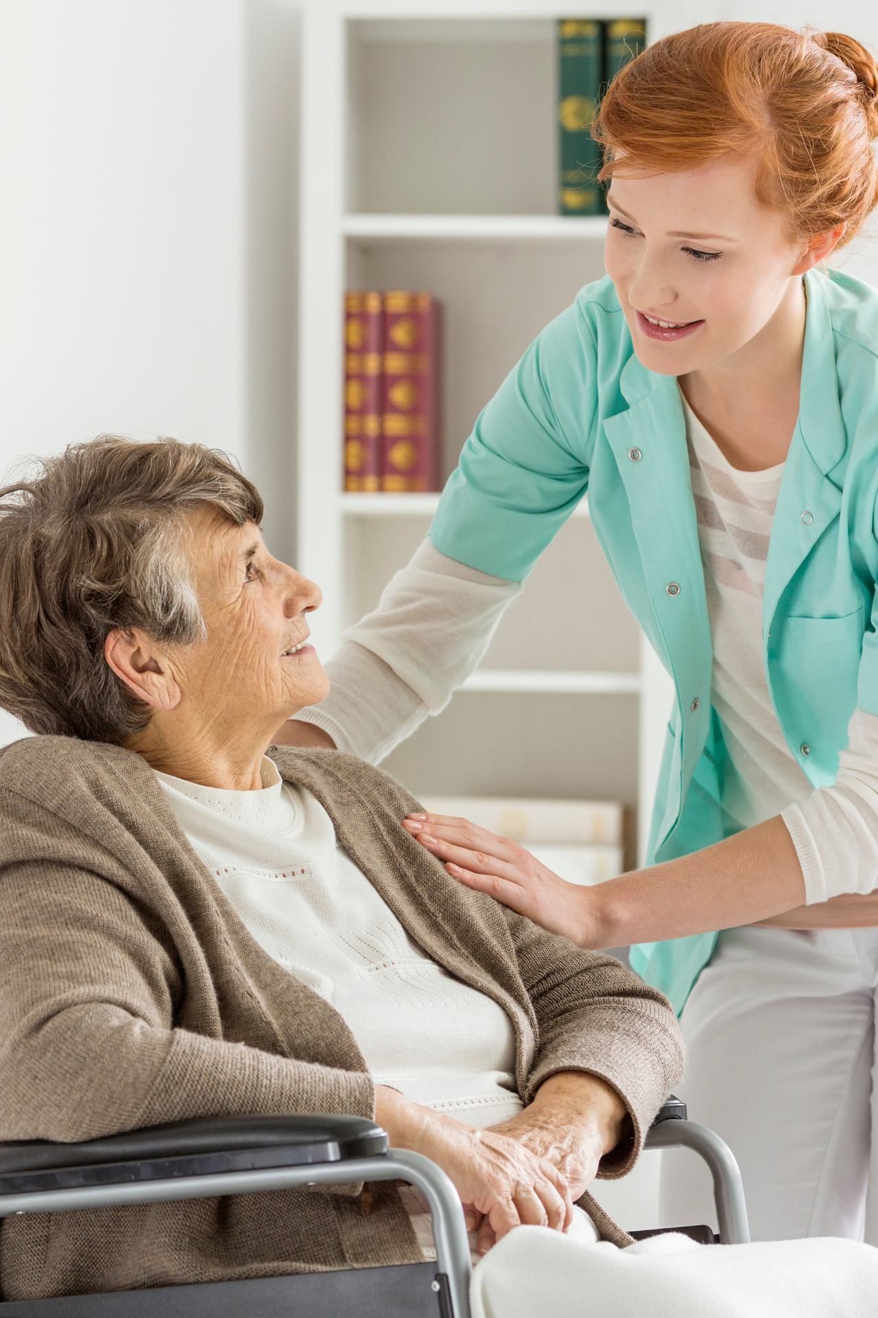 A nurse visits with an elderly woman in a wheelchair during a home nurse visit, a nursing home alternative